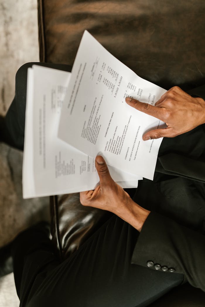Close-up of a business professional reading and pointing at financial documents.